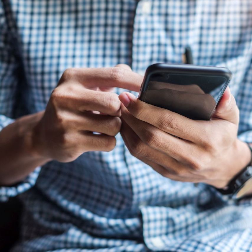 Young casual Businessman holding and using smartphone for sms messages, hipster man typing touchscreen cell phone in the cafe. business, lifestyle, technology and Social media network concept