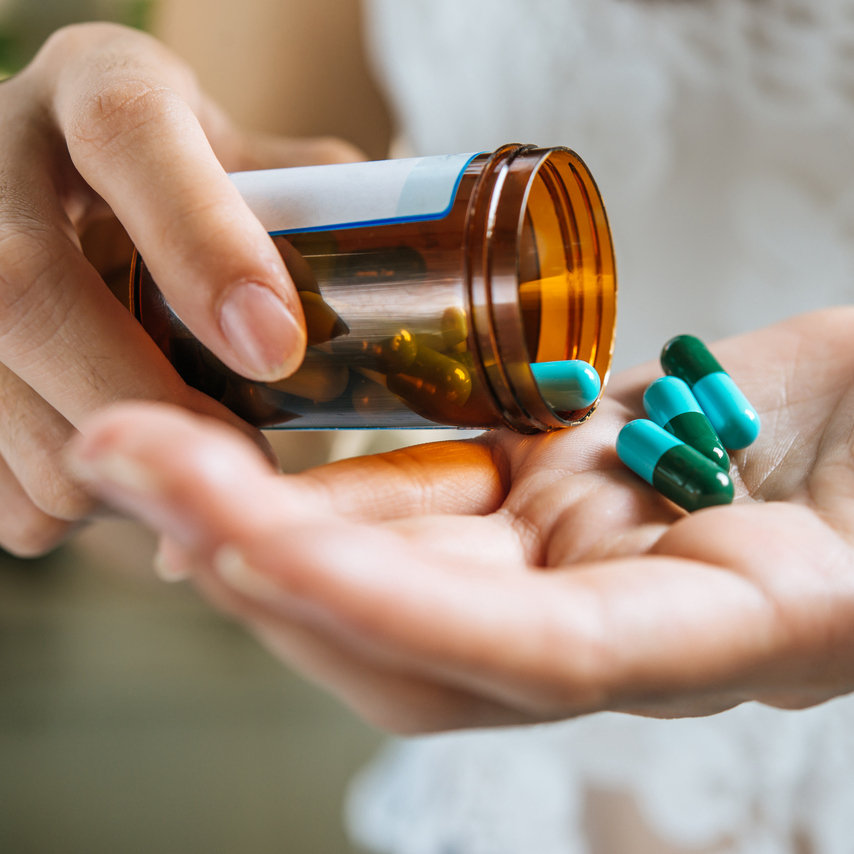 woman s hand pours medicine pills out bottle